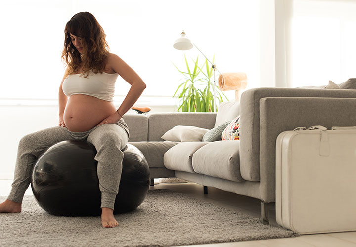 Pregnant woman exercising on medicine ball