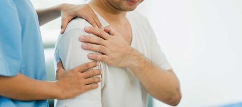 Doctor examining man with rotator cuff shoulder pain