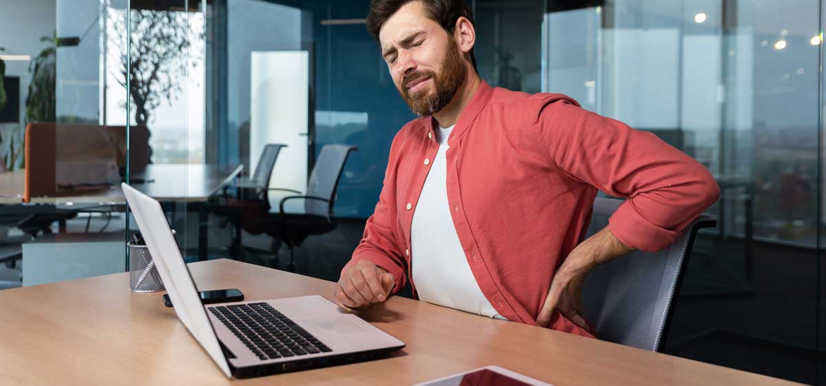 Man with back pain sitting at workstation